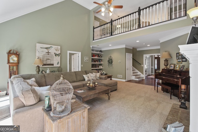 living room featuring ceiling fan, carpet, a towering ceiling, and ornamental molding