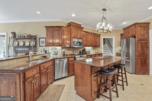 kitchen featuring hanging light fixtures, sink, stainless steel appliances, and a center island