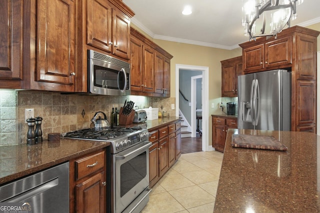 kitchen featuring light tile patterned floors, stainless steel appliances, decorative backsplash, decorative light fixtures, and ornamental molding