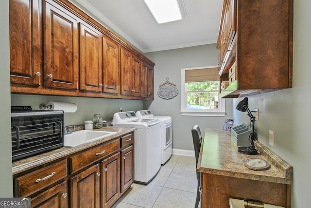 clothes washing area featuring washing machine and dryer, cabinets, sink, light tile patterned flooring, and crown molding