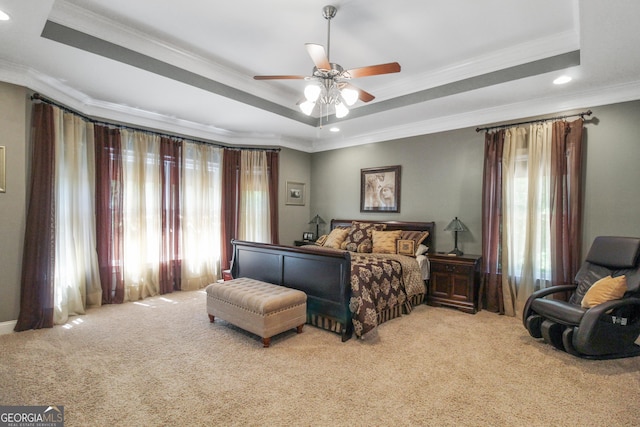 carpeted bedroom featuring ceiling fan, crown molding, and a tray ceiling