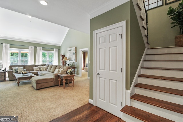 living room with vaulted ceiling, dark colored carpet, and ornamental molding