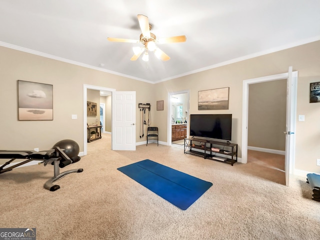 workout area featuring ceiling fan, light colored carpet, and ornamental molding