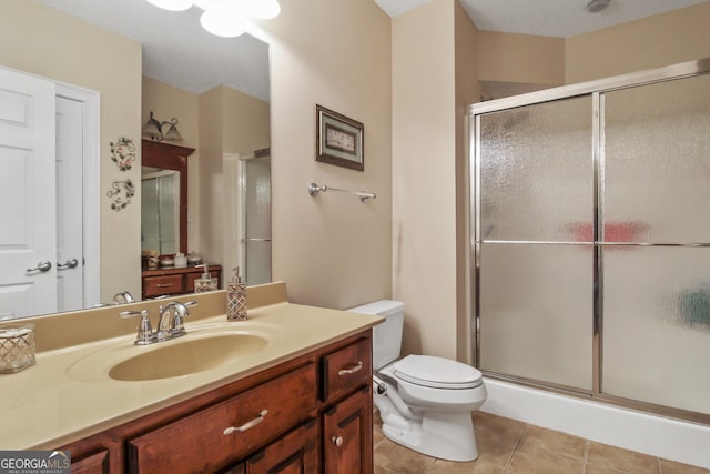 bathroom featuring toilet, vanity, tile patterned flooring, and a shower with door