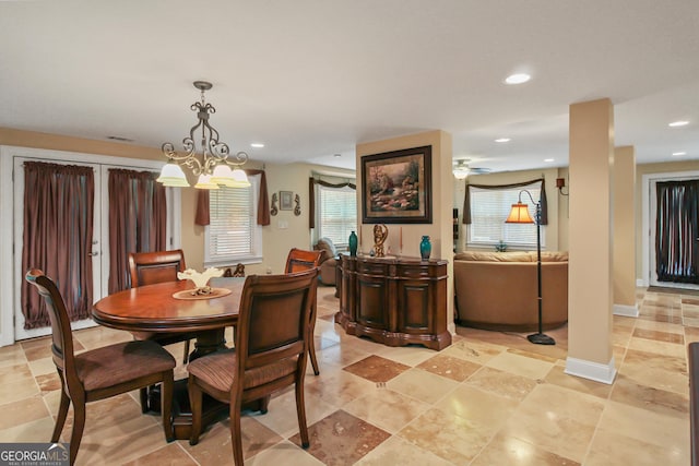 dining room with ceiling fan with notable chandelier and a wealth of natural light