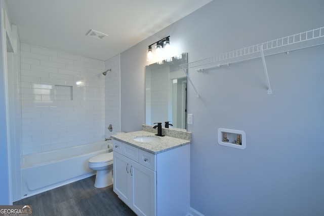 full bathroom featuring hardwood / wood-style flooring, toilet, vanity, and tiled shower / bath