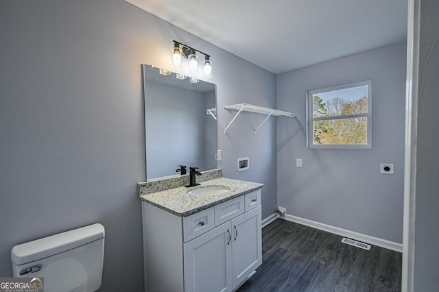 bathroom with hardwood / wood-style floors, toilet, and vanity