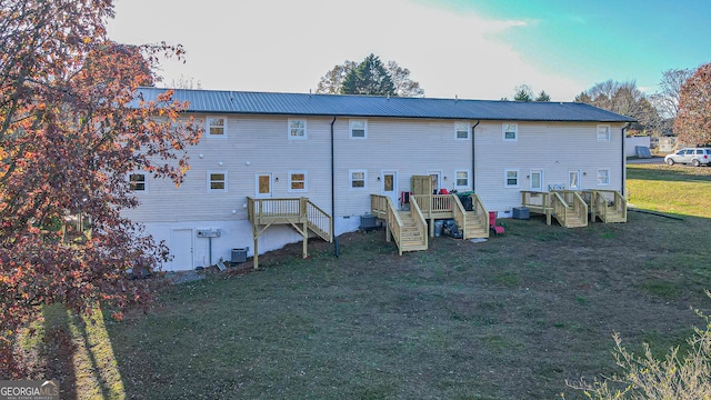 rear view of property with a wooden deck, a yard, and central AC