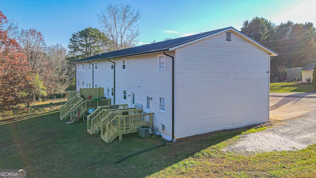 view of property exterior featuring a wooden deck, cooling unit, and a lawn