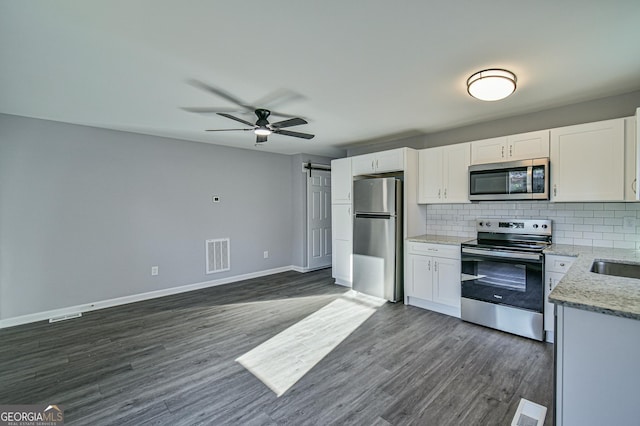 kitchen featuring ceiling fan, appliances with stainless steel finishes, white cabinets, dark wood-type flooring, and backsplash