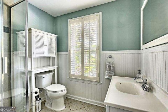 bathroom with toilet, a healthy amount of sunlight, tile patterned flooring, and vanity