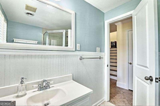 bathroom with tile patterned floors, a shower with door, and sink