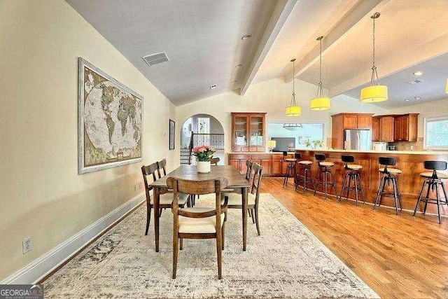 dining room featuring vaulted ceiling with beams and light hardwood / wood-style floors