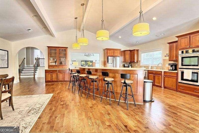 kitchen featuring pendant lighting, stainless steel appliances, vaulted ceiling with beams, and tasteful backsplash