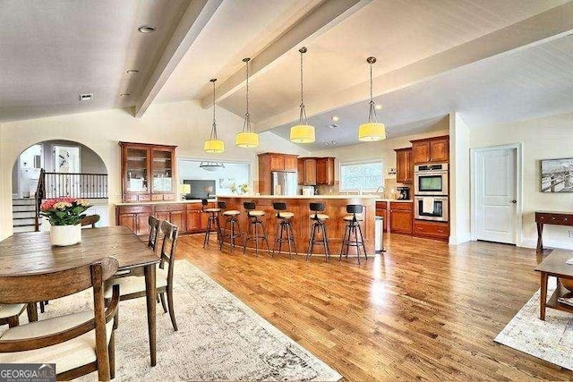 dining room with light hardwood / wood-style flooring and vaulted ceiling with beams