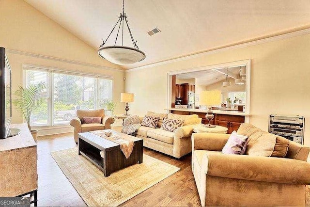 living room with visible vents, wood finished floors, lofted ceiling, and ornamental molding