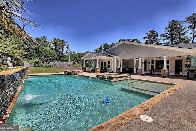 view of pool with a patio area, fence, and a pool with connected hot tub