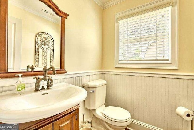 bathroom featuring toilet, vanity, and ornamental molding