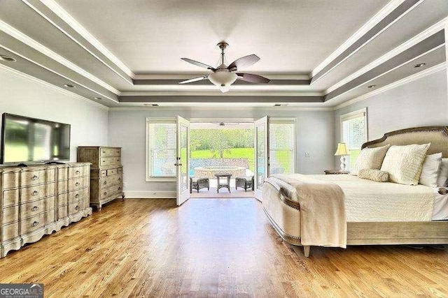 bedroom with ceiling fan, a tray ceiling, and ornamental molding