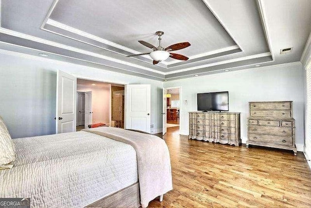 bedroom featuring ceiling fan, a tray ceiling, ornamental molding, and hardwood / wood-style flooring