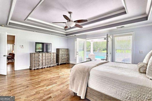 bedroom with hardwood / wood-style floors, access to exterior, ornamental molding, a raised ceiling, and ceiling fan