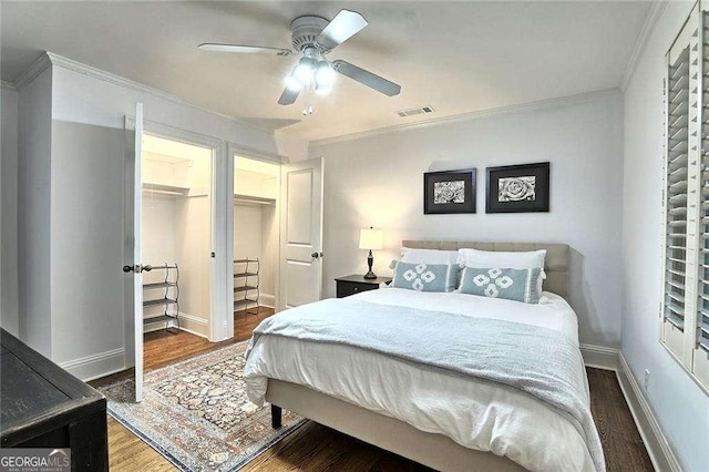 bedroom with a spacious closet, ceiling fan, dark hardwood / wood-style floors, a closet, and crown molding