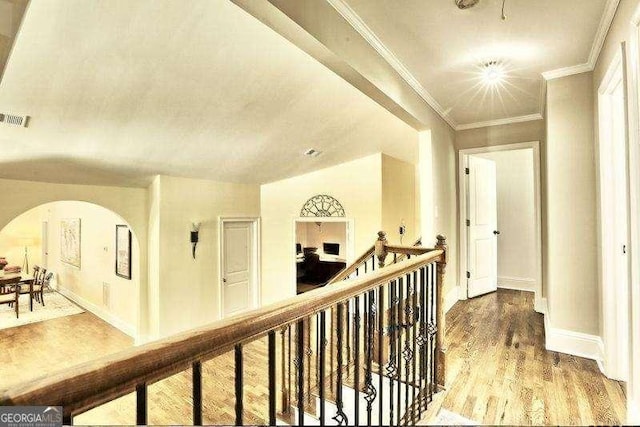 corridor with vaulted ceiling, ornamental molding, and hardwood / wood-style flooring