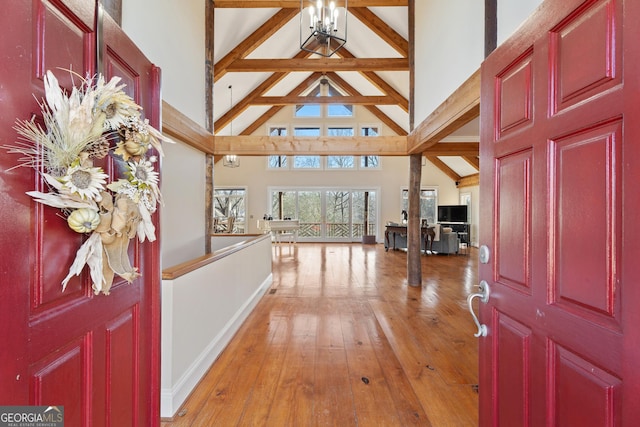 foyer entrance featuring light wood-type flooring, beamed ceiling, a chandelier, and high vaulted ceiling