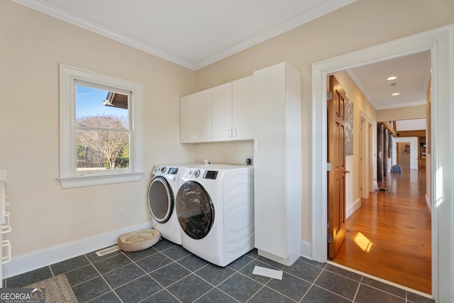 washroom with washing machine and dryer, dark tile patterned flooring, crown molding, and cabinets