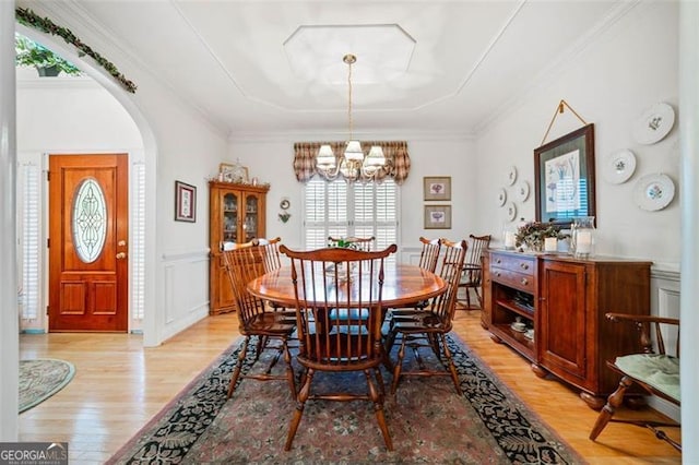 dining area featuring light wood-type flooring, a chandelier, and crown molding