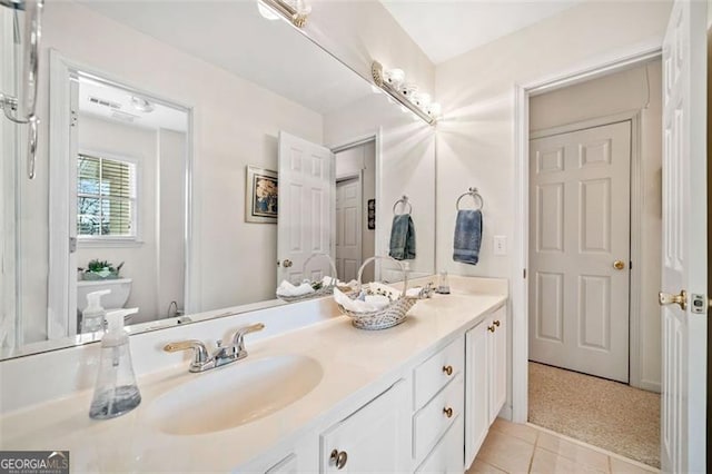 bathroom with toilet, vanity, and tile patterned flooring