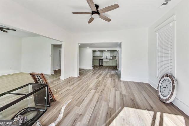 living room featuring ceiling fan, sink, and light hardwood / wood-style flooring