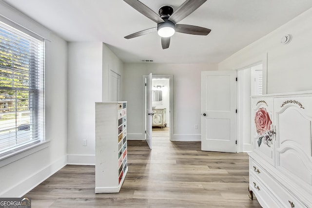 bedroom featuring ceiling fan, connected bathroom, light hardwood / wood-style flooring, and multiple windows