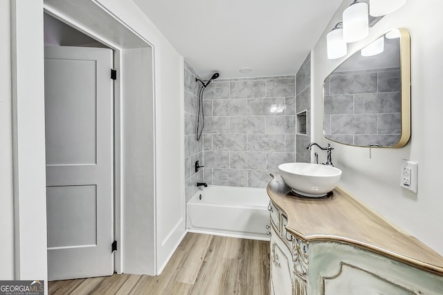 bathroom with wood-type flooring, vanity, and tiled shower / bath