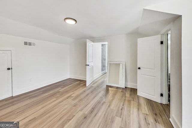 additional living space featuring vaulted ceiling and light hardwood / wood-style flooring