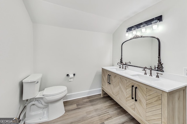 bathroom featuring wood-type flooring, toilet, vanity, and vaulted ceiling