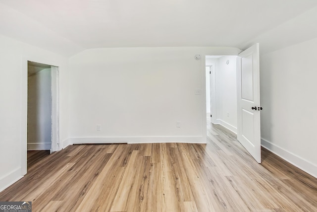 unfurnished room with lofted ceiling and light wood-type flooring