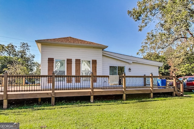 rear view of house with a deck and a yard