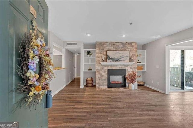 unfurnished living room with hardwood / wood-style flooring and a stone fireplace