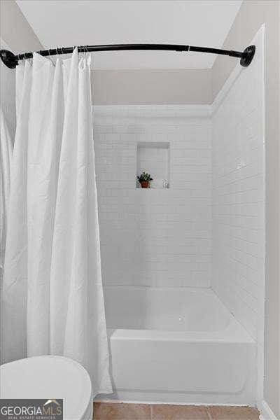 bathroom with tile patterned floors, toilet, and shower / bath combo