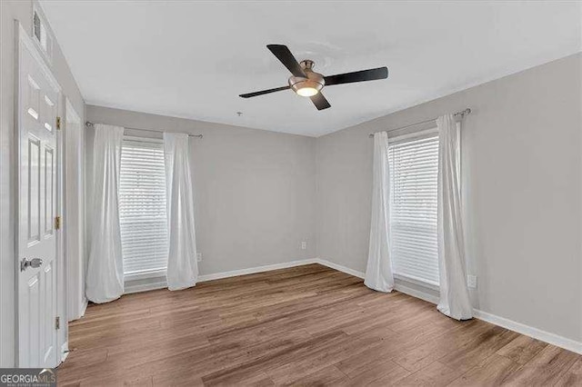 unfurnished room with ceiling fan, hardwood / wood-style floors, and a wealth of natural light