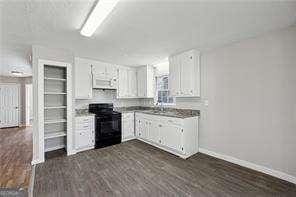 kitchen featuring dark wood-type flooring, white cabinets, sink, and black range with electric cooktop