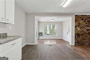 interior space with light stone countertops, white cabinets, and dark hardwood / wood-style flooring