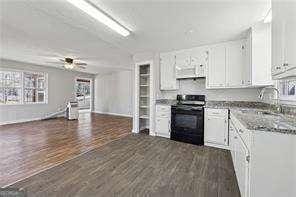 kitchen with exhaust hood, dark hardwood / wood-style floors, black range with electric stovetop, sink, and white cabinetry