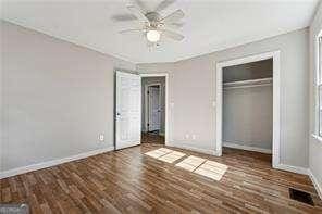 unfurnished bedroom featuring ceiling fan, a closet, and dark wood-type flooring