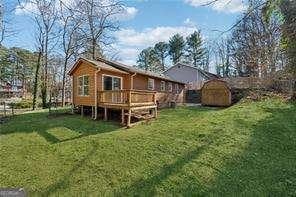 back of property featuring a deck, a shed, and a yard