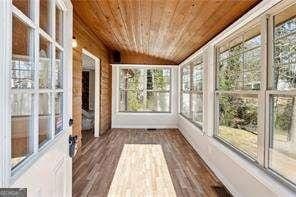 unfurnished sunroom featuring vaulted ceiling, wooden ceiling, and a wealth of natural light