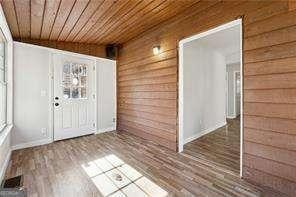 interior space featuring wooden ceiling, hardwood / wood-style floors, lofted ceiling, and wooden walls