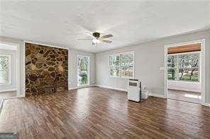 unfurnished living room featuring ceiling fan and dark hardwood / wood-style flooring