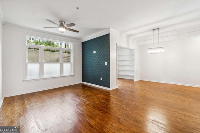 unfurnished room featuring ceiling fan, built in shelves, crown molding, and hardwood / wood-style flooring